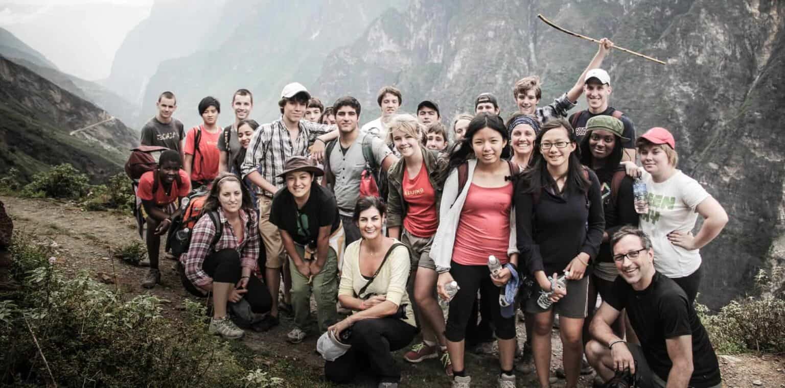 Diverse group of students on outdoor educational trip with teachers in scenic mountain landscape.