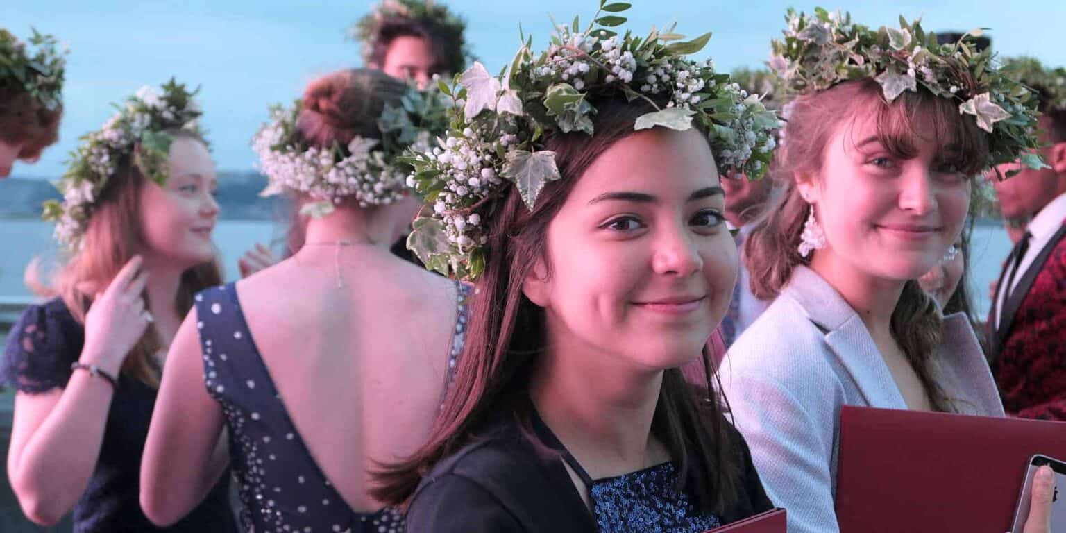 Young women wearing flower crowns at a graduation ceremony celebrating academic success and cultural traditions.