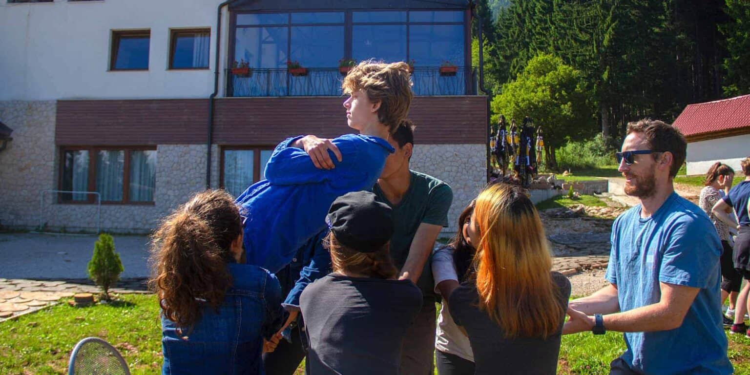 Young students and teachers engaging in outdoor activities at a modern, scenic international school campus.