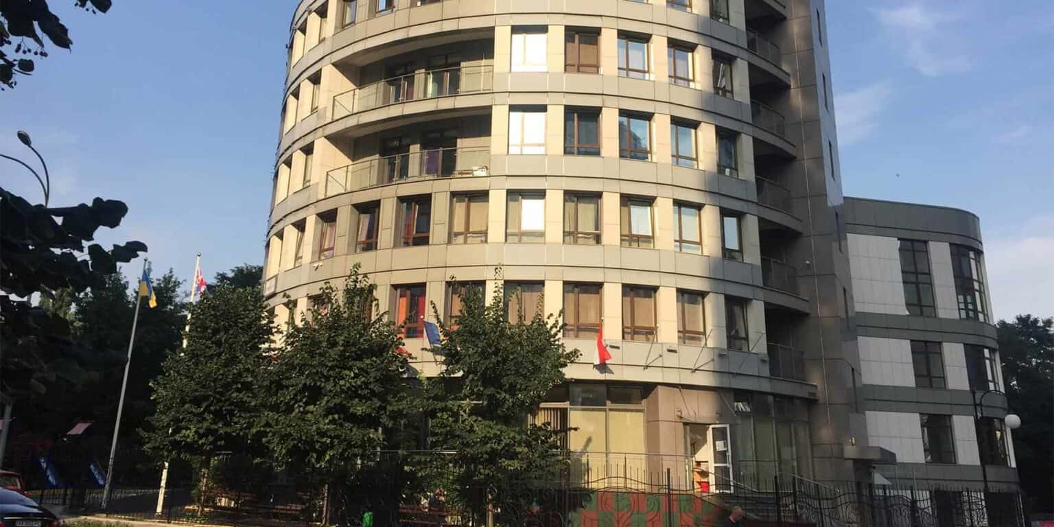 Modern multi-story building at a world school campus with flags and lush greenery.