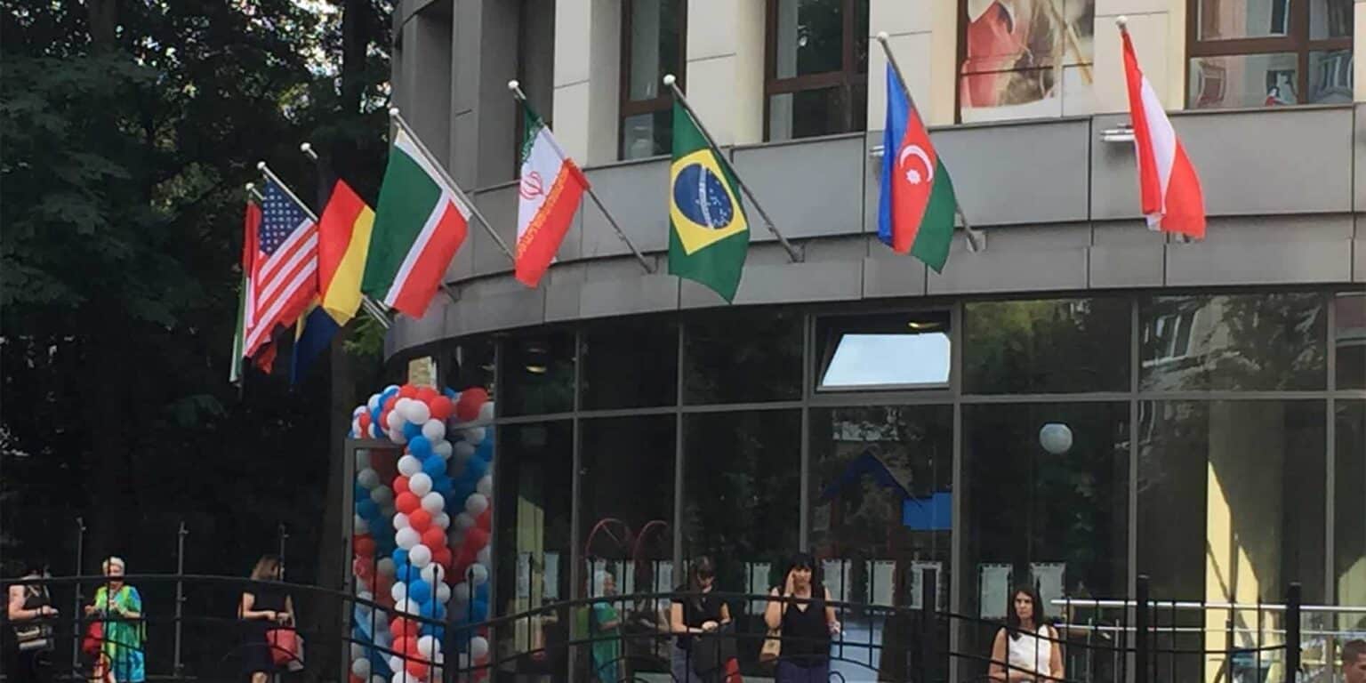 International school flags displayed outside a modern building for global education.