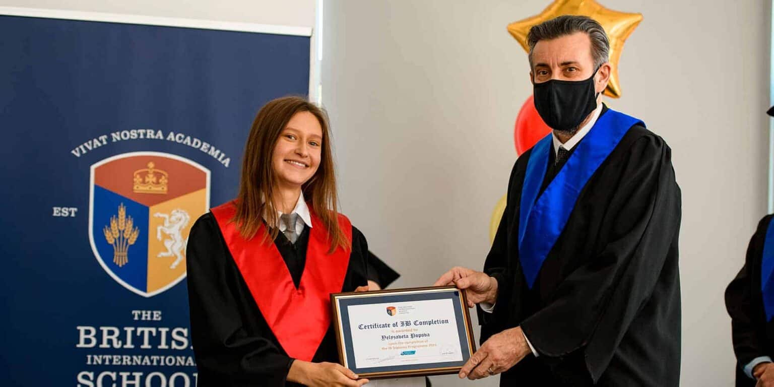 Young student receiving certificate at World Schools graduation ceremony, celebrating academic achievement.