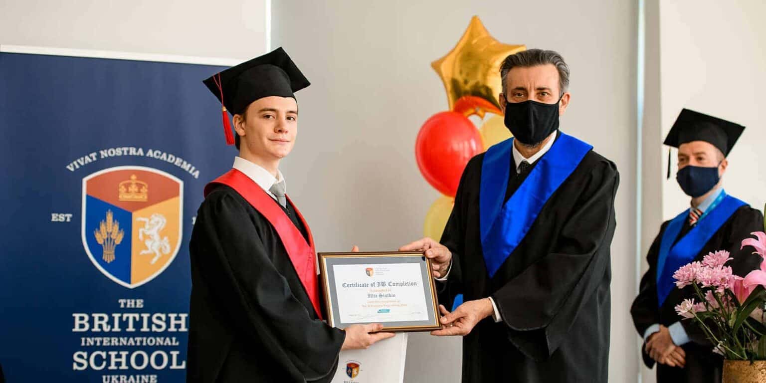 Young graduate receiving diploma at British International School ceremony, emphasizing academic excellence and international education.