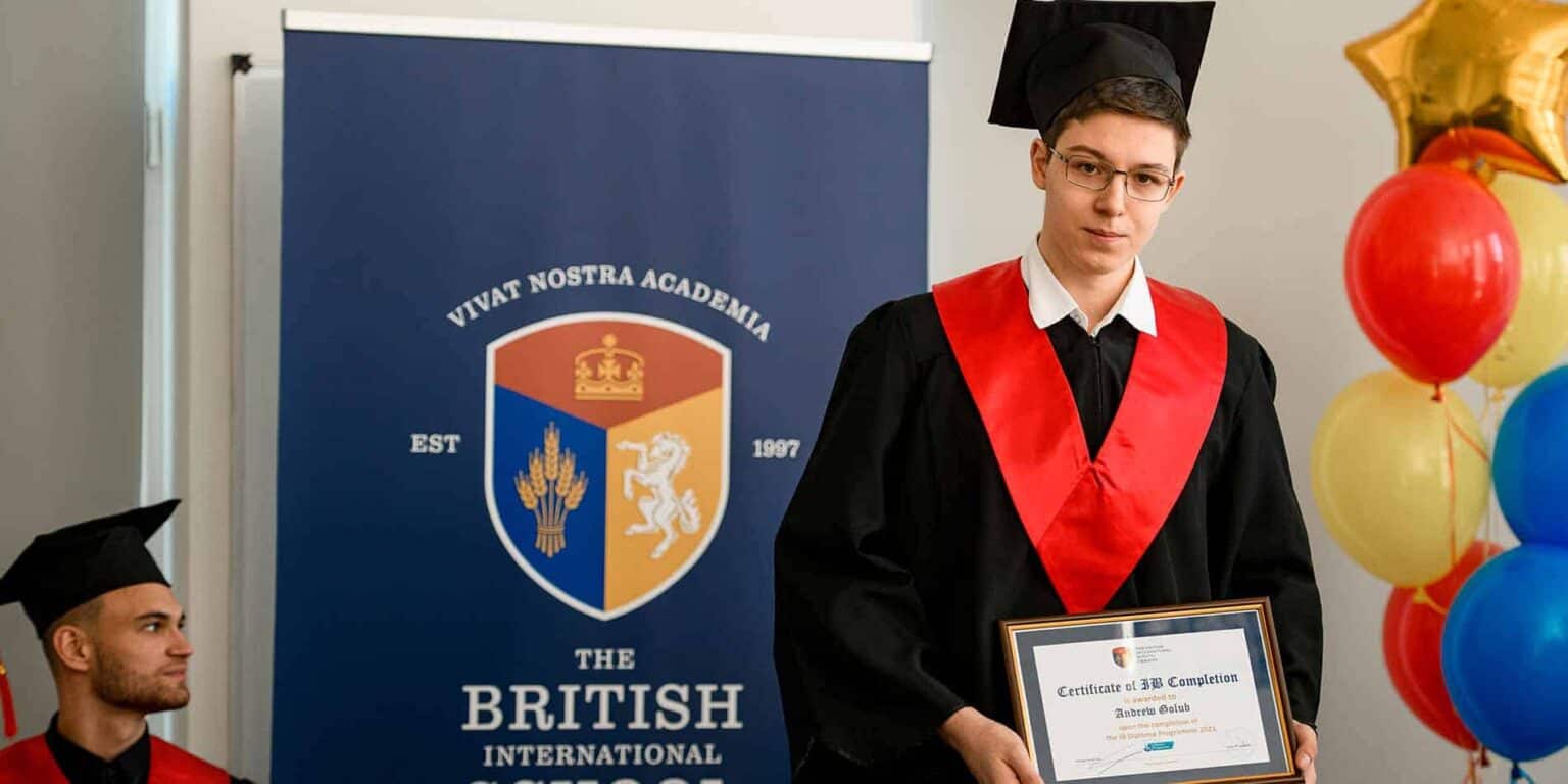 Graduate in academic gown holding certificate at World Schools graduation ceremony.