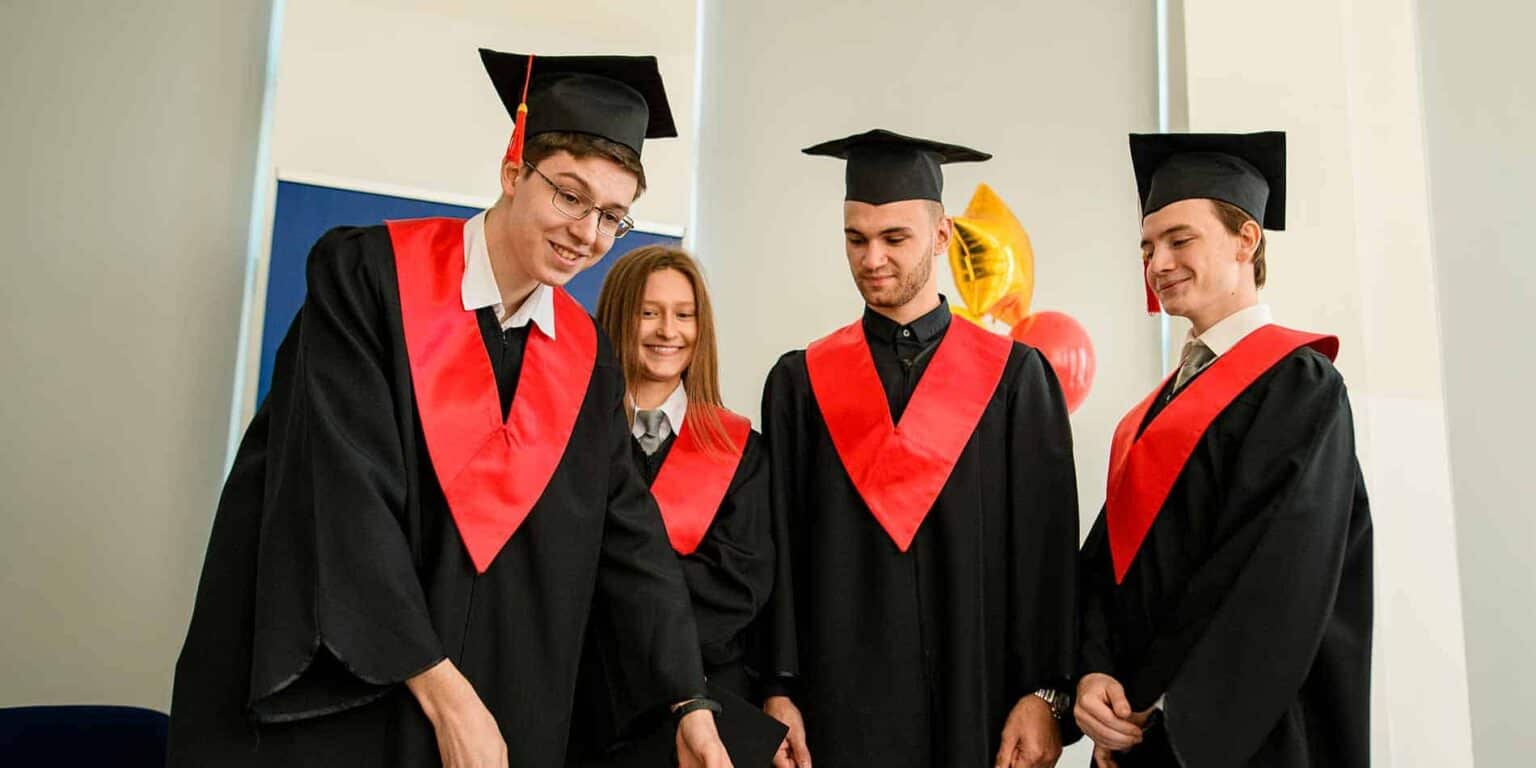 Graduates celebrating at a school graduation ceremony, wearing caps and gowns in a modern educational setting.