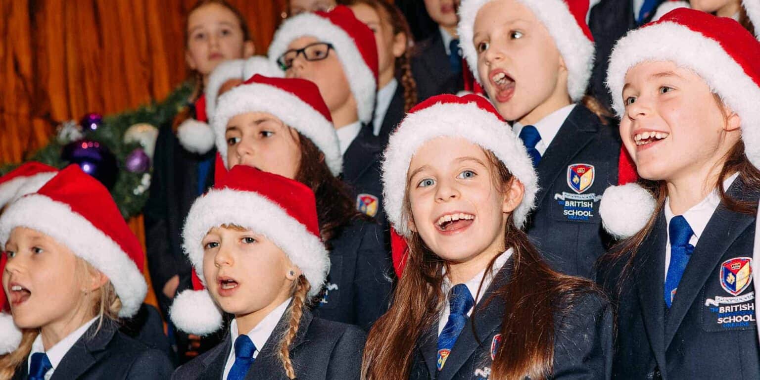 Festive schoolchildren wearing Santa hats performing during holiday celebration at British School Ukraine.