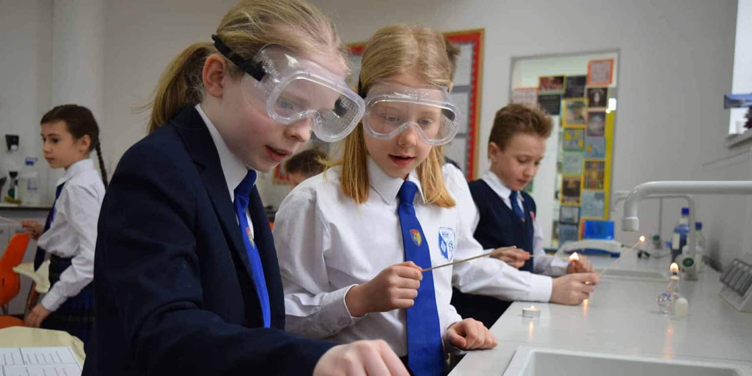 Children conducting a science experiment in a classroom, exploring chemistry with safety goggles.