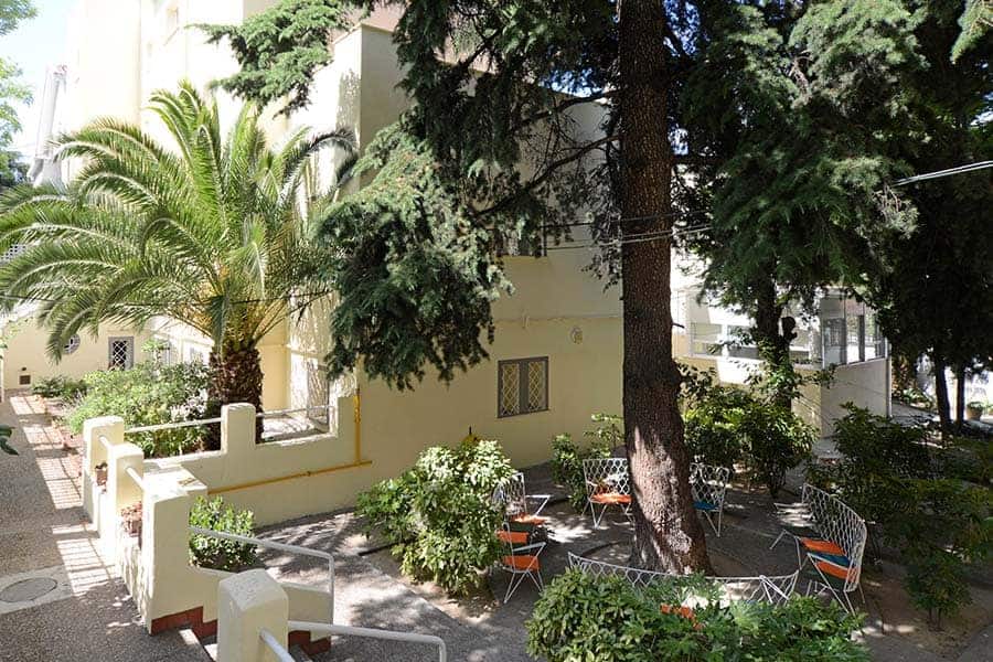 Lush school garden with large trees and outdoor seating for students' relaxation and outdoor activities.