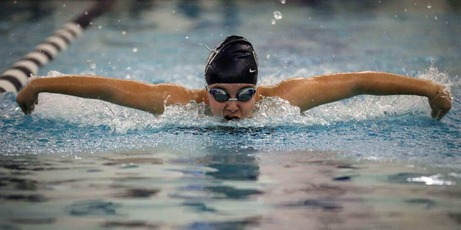 Focused swimmer in competitive swimming race at a professional pool.