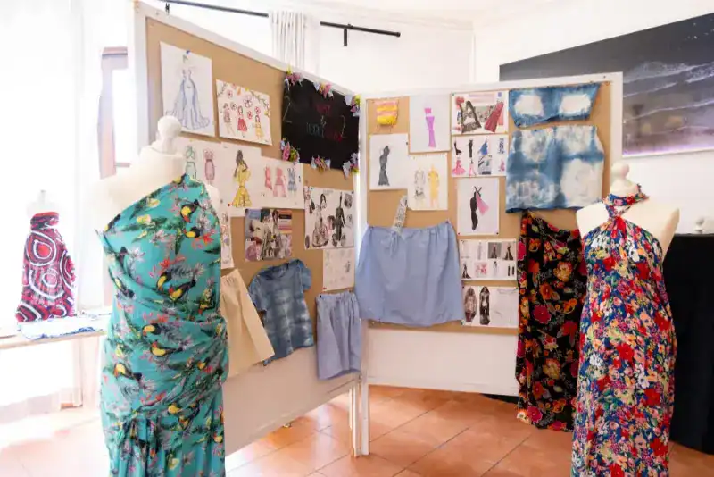 This Month at TASIS: June 2024 17 Colorful fashion design display featuring fabric swatches and clothing sketches at a world schools event.