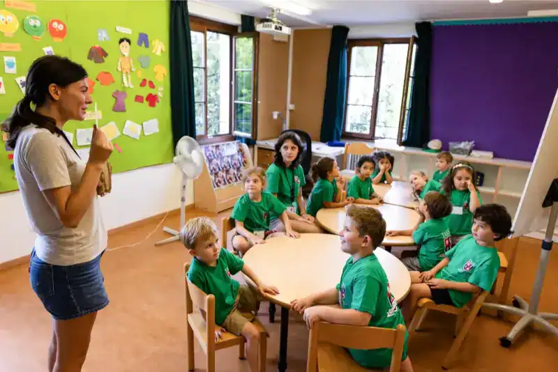 This Month at TASIS: June 2024 21 Young teacher engaging students in classroom activities at an international school.