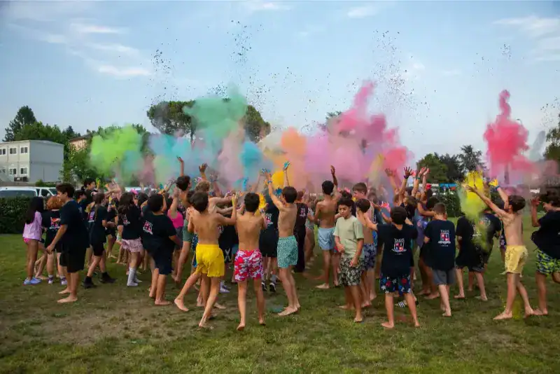 This Month at TASIS: June 2024 26 Brightly colored powders celebrating school event with children outdoors during festival.