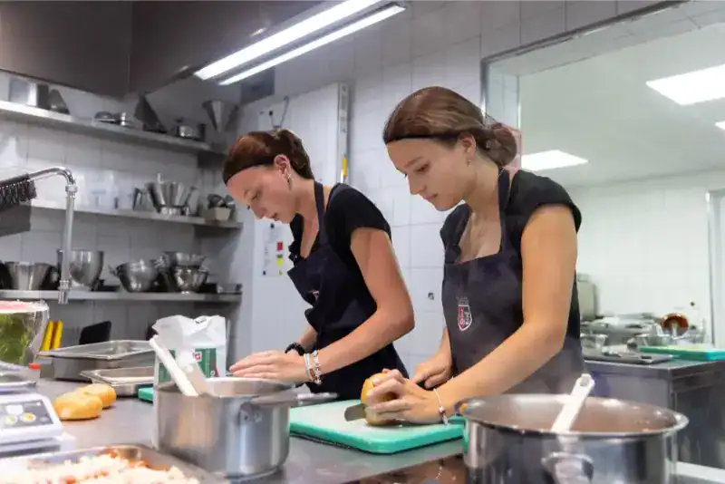 This Month at TASIS: June 2024 30 Students cooking in a professional kitchen at a world school culinary program.