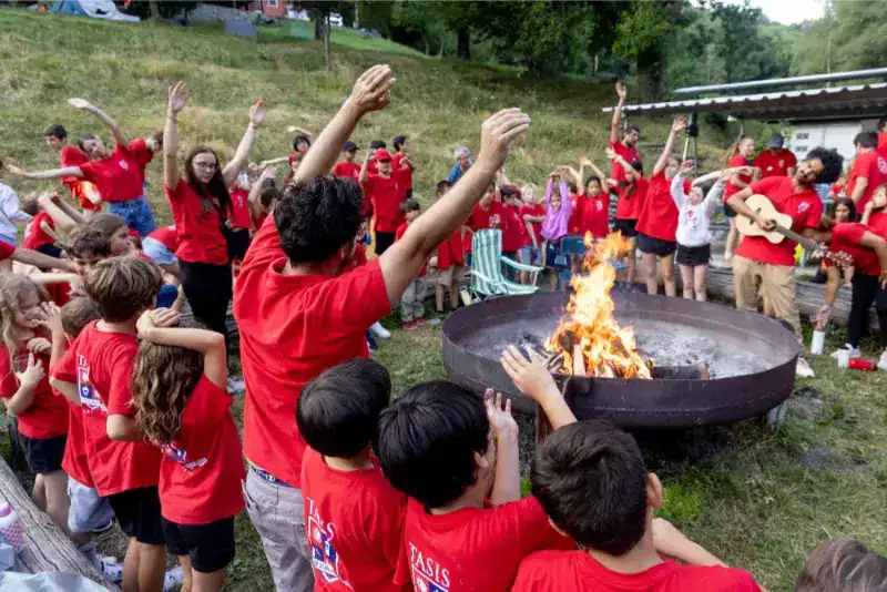 This Month at TASIS: June 2024 36 Exciting outdoor school event with children gathered around a campfire practicing fire safety.