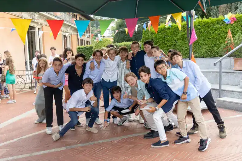 This Month at TASIS: June 2024 38 Vibrant group of students celebrating outdoors at a school event with colorful banners and joyful atmosphere.