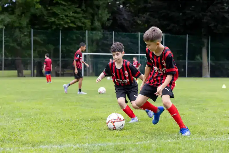 This Month at TASIS: June 2024 5 Kids playing soccer on a school field, promoting youth sports and physical activity.