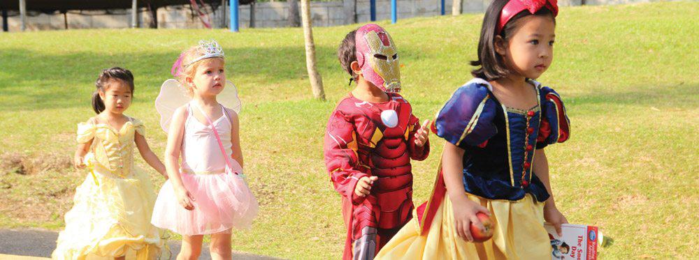 Colorful children in costumes enjoying outdoor activities at World Schools event.