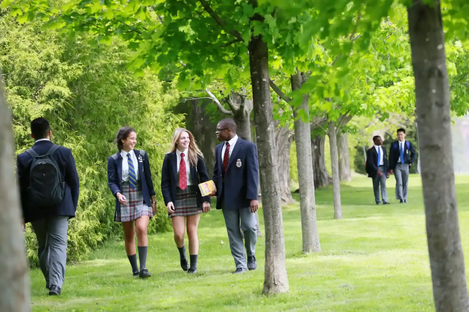 Students walking outdoors in a lush green schoolyard, emphasizing world schools and quality education.