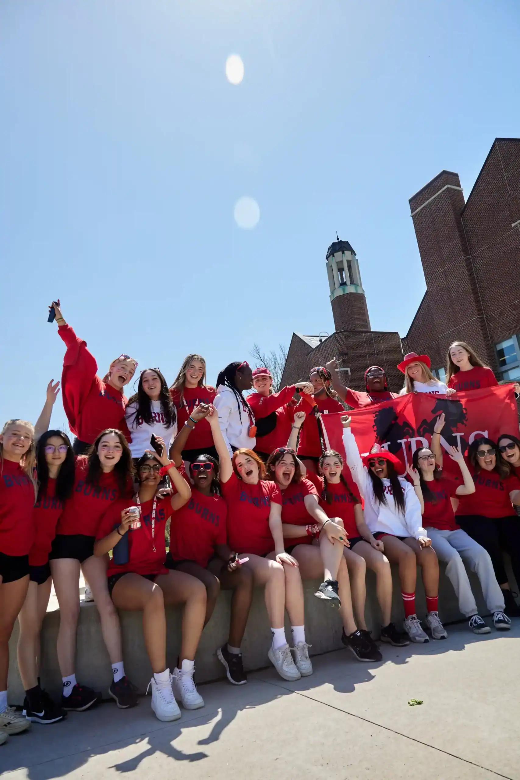 Bright diverse international students celebrating on school campus with school banner, promoting global education excellence.