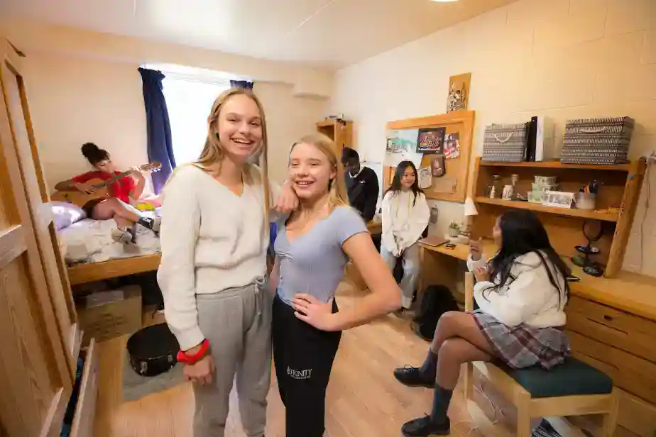 Brightly lit student dorm room with diverse students engaging in various activities, promoting inclusive and international learning environments.