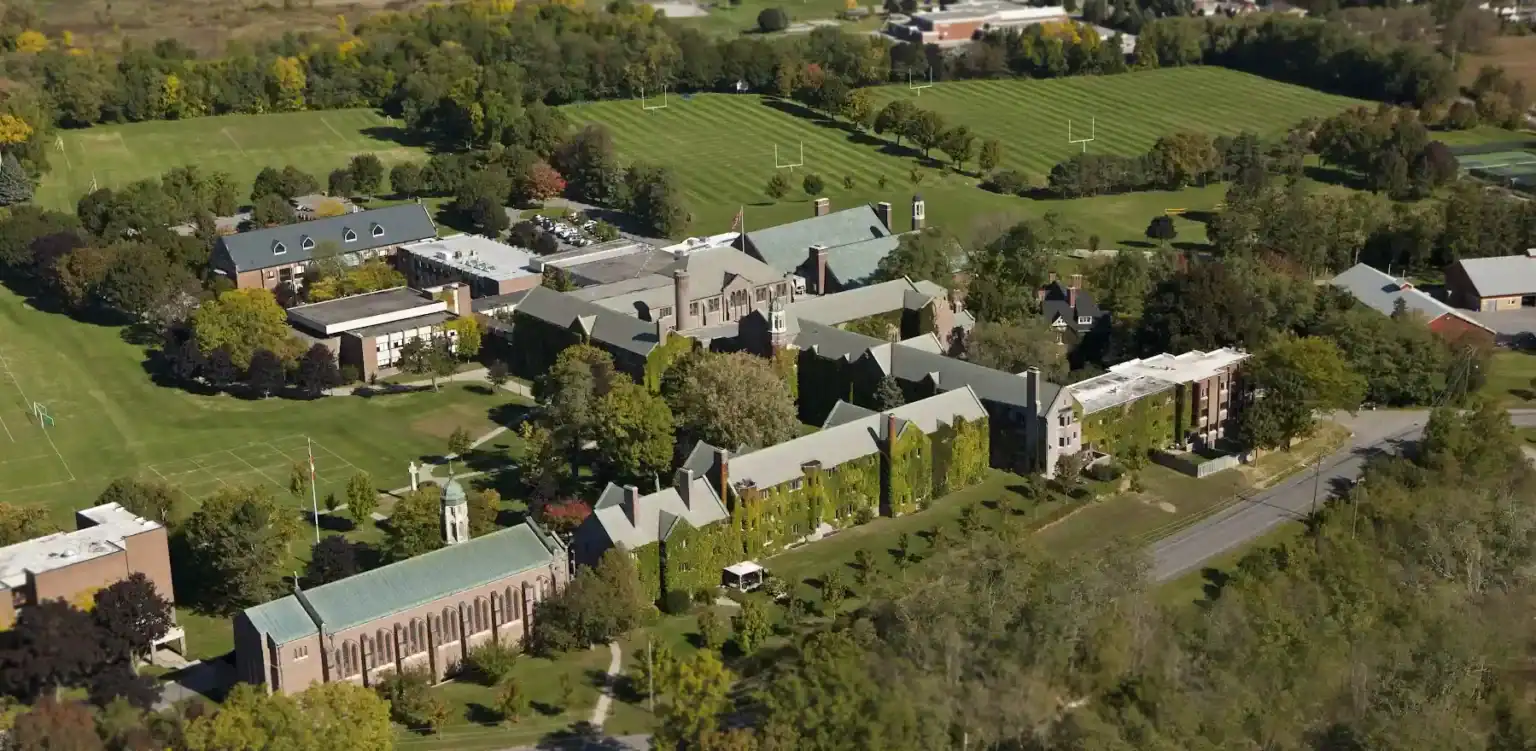 Historic private school campus with lush green fields and classic architecture, ideal for student learning and sports.