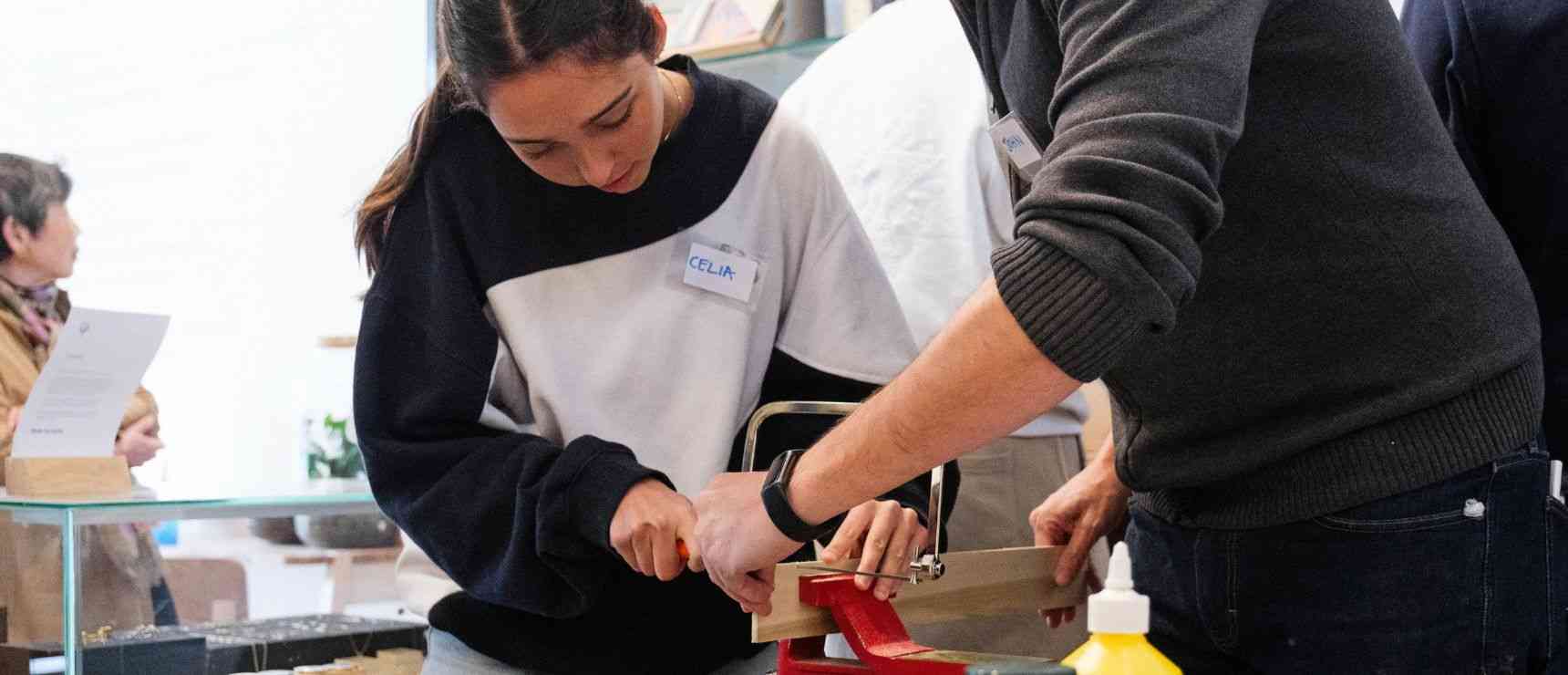 Young student cutting wood during workshop at World Schools event for hands-on learning and skill development.