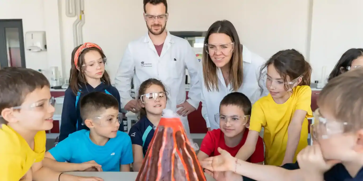 Kids science experiment in classroom with teacher and students, highlighting innovative learning at World Schools.