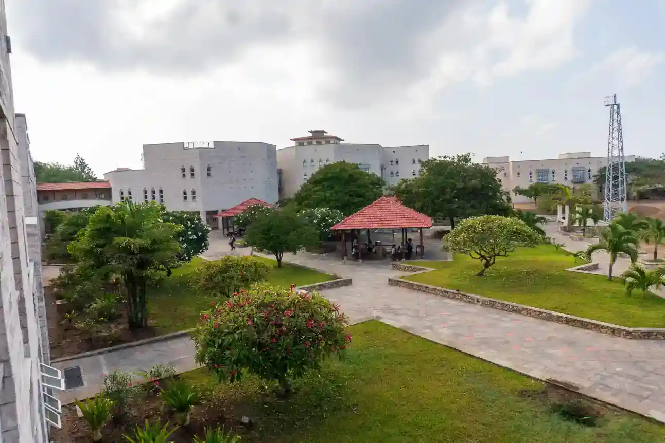 حرم مدرسي حديث مع مساحات خضراء مورقة ومناطق جلوس مظللة للطلاب.