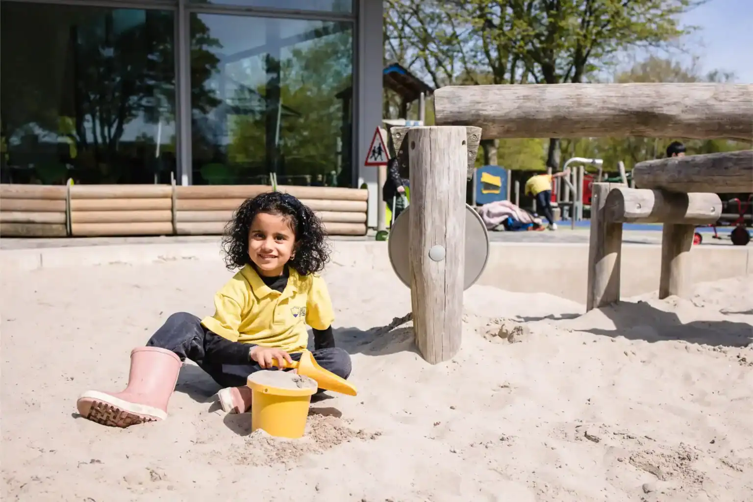 小女孩在世界学校操场的户外沙池中玩耍。.