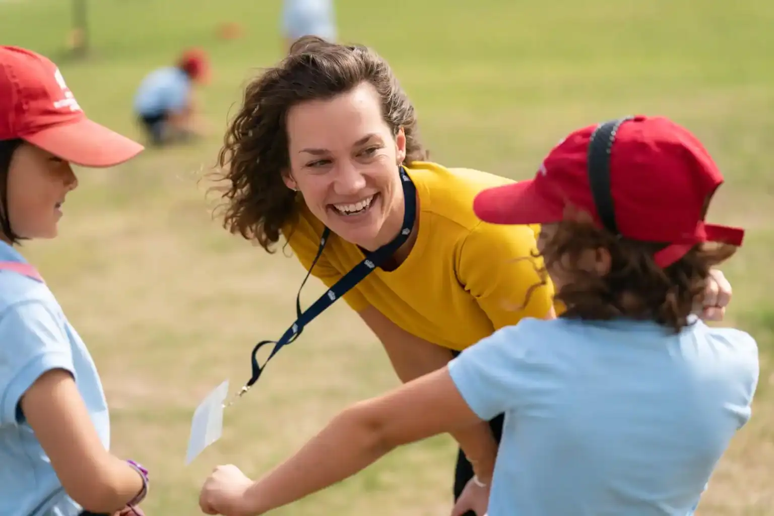 Enthusiastic teacher engaging children in outdoor school activity for global education and leadership development.