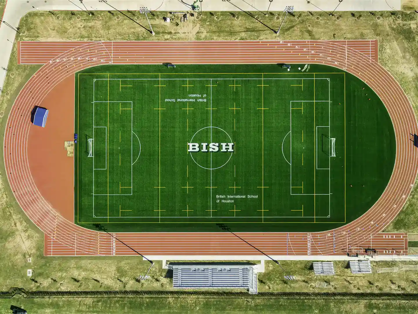 Sunny athletic field featuring a soccer pitch and running track at British International School of Houston for sports excellence.