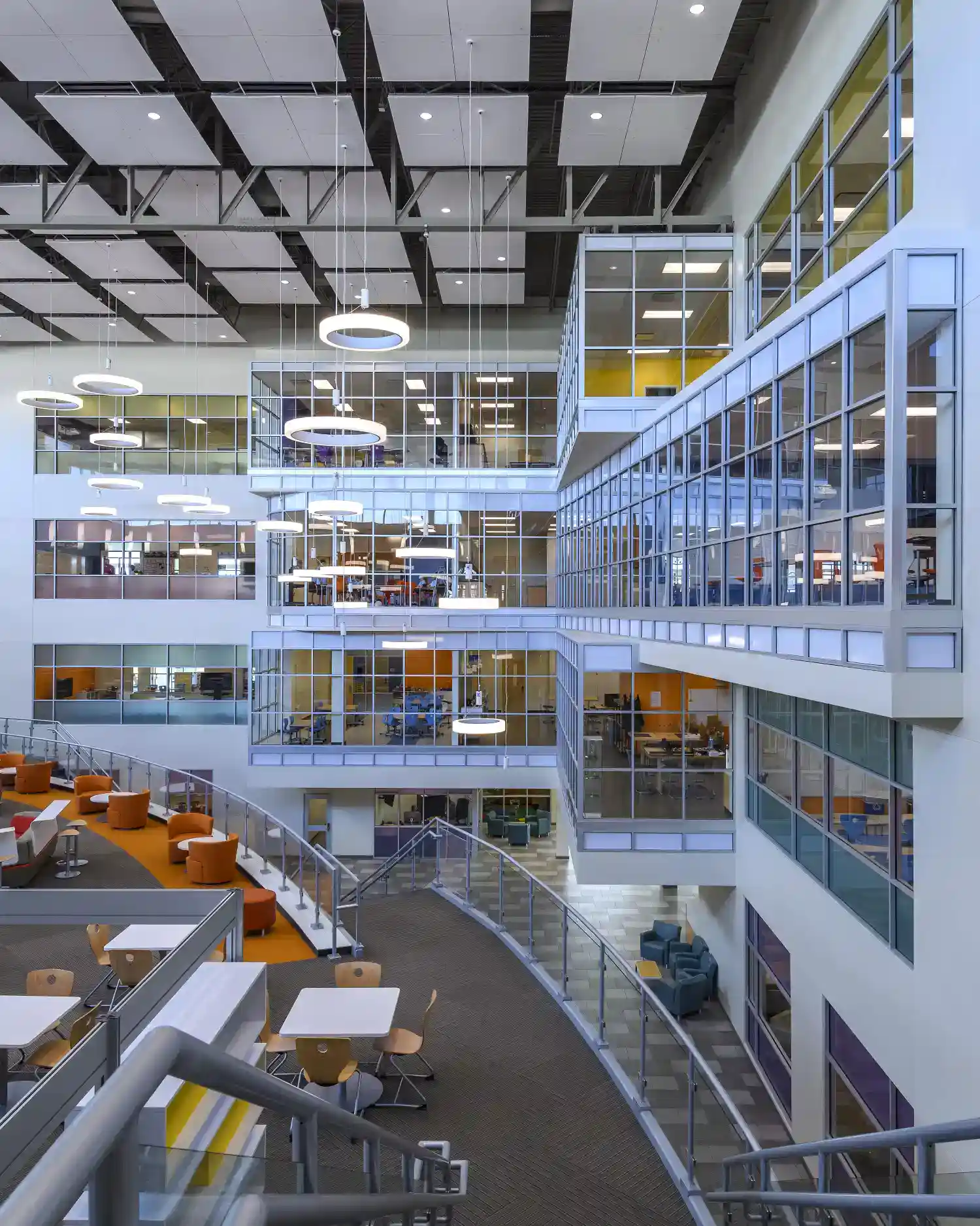 Bright modern school interior with glass classrooms, open spaces, and contemporary furnishings.
