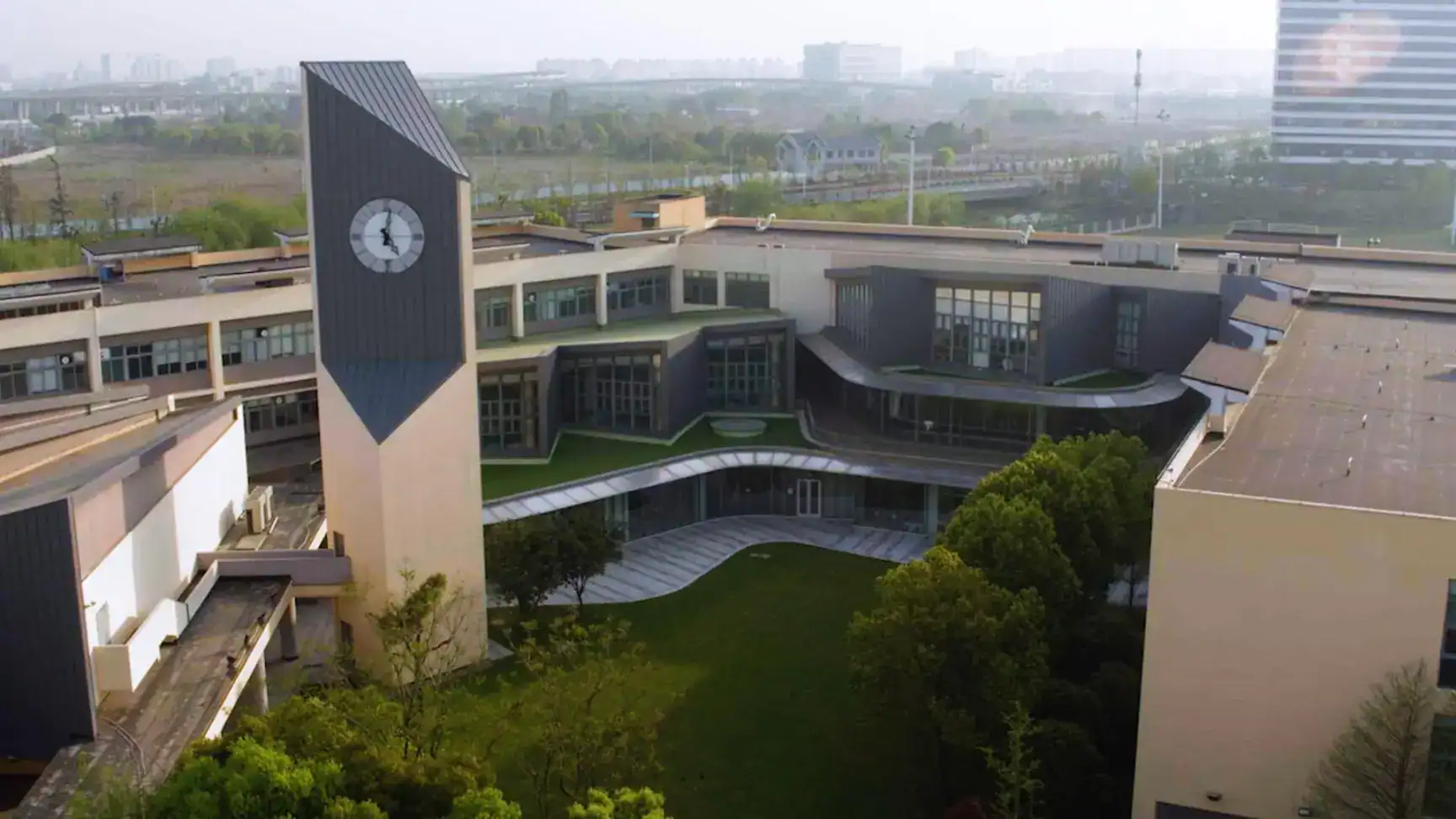Modern international school campus with central clock tower and green outdoor areas, ideal for global students.