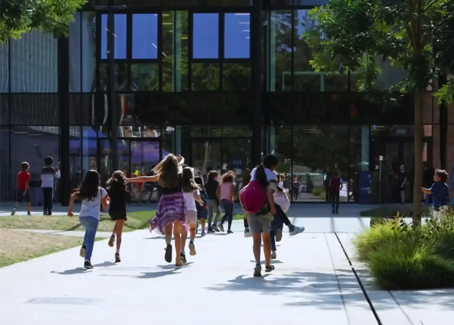 Children running outside at a modern school building, promoting international education and global learning environments.