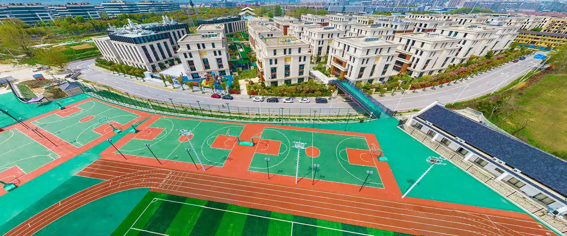 Modern international school campus with sports facilities and green spaces for student activities.