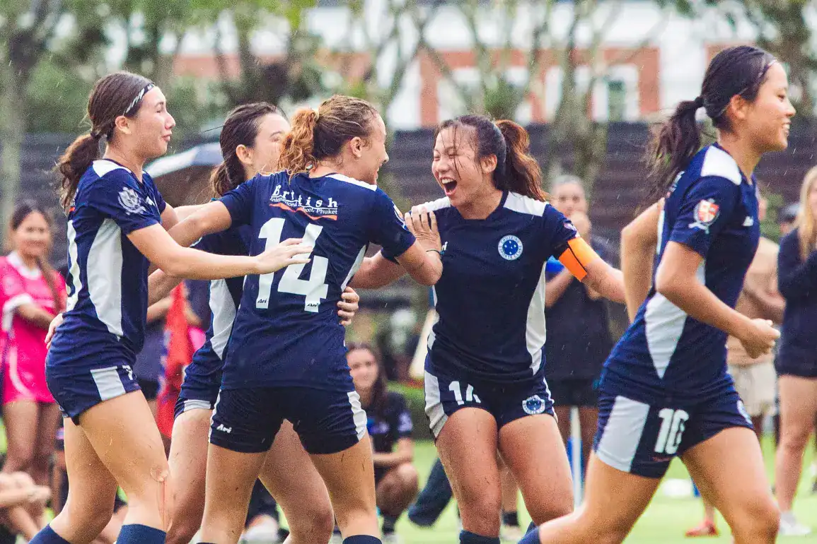 Jóvenes jugadoras de fútbol celebran la victoria en el campo, mostrando el trabajo en equipo y la excelencia deportiva.