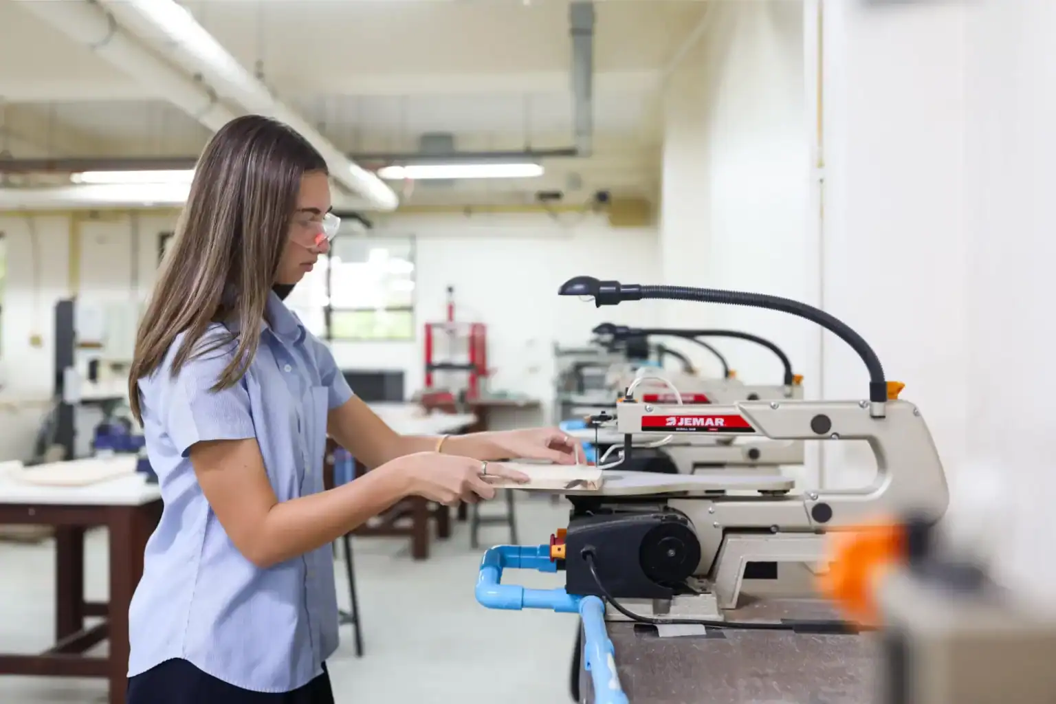 Estudiante de secundaria trabajando con una máquina para trabajar la madera en el aula, centrada en la educación STEM.