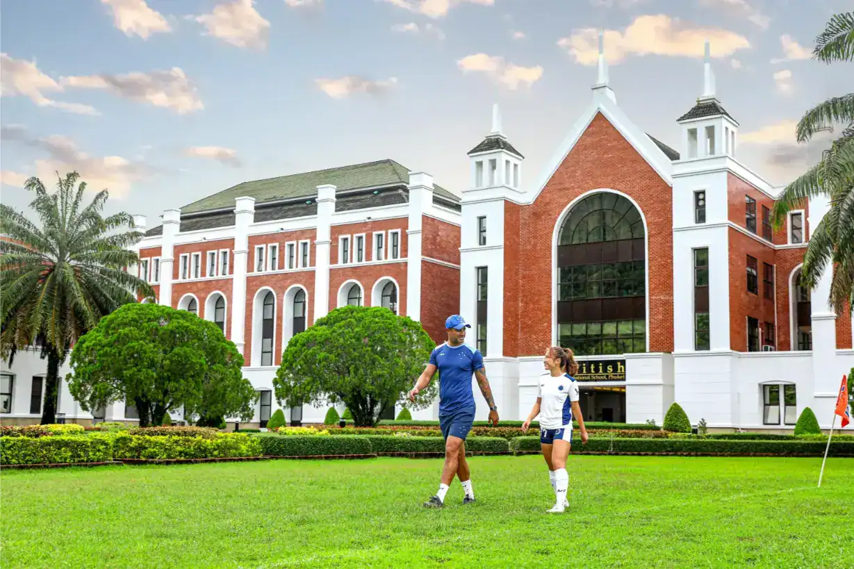 Moderno campus escolar internacional con instalaciones deportivas y exuberante vegetación, que fomenta la excelencia educativa global.