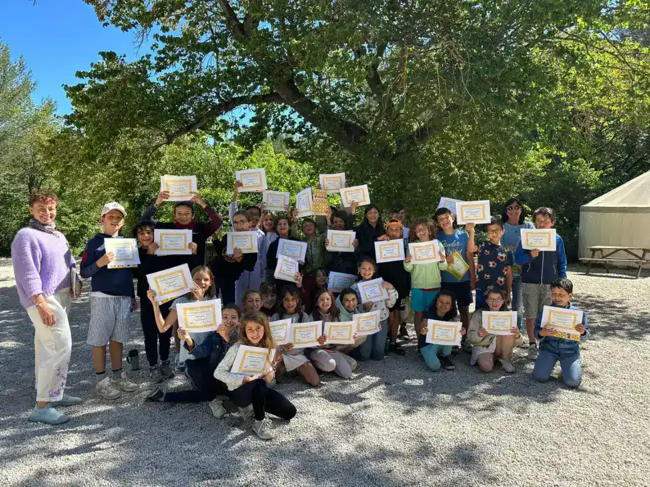 Students holding awards outdoors at World Schools, celebrating academic achievement in a lush green setting.