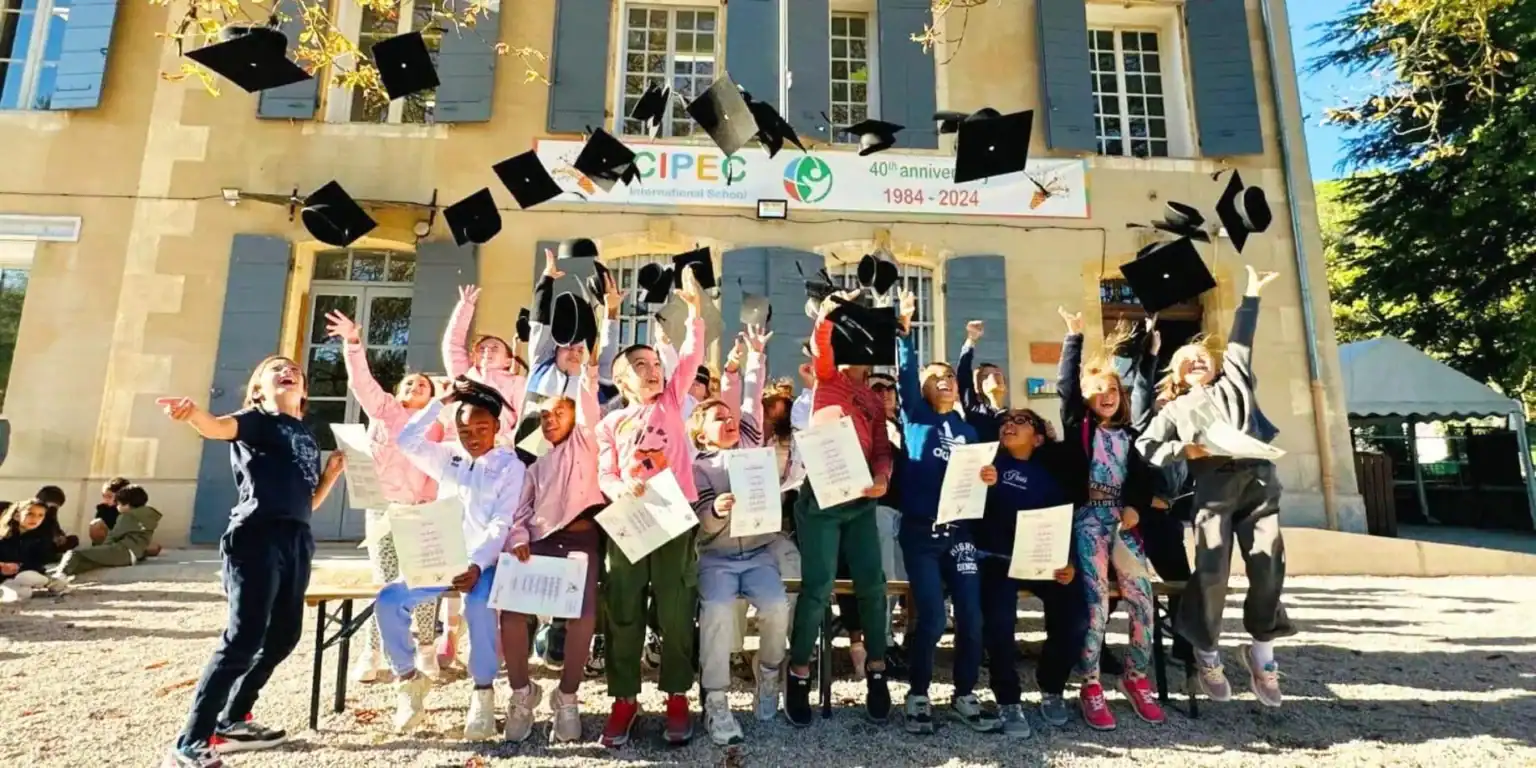 Graduates celebrating outside a school building during graduation day with caps thrown in the air.