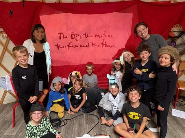 1. Group of diverse children and teachers engaging in a theatrical storytelling activity at World Schools.