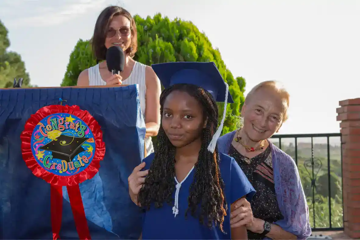 Joyful graduation celebration with student in cap and gown, proud family, and outdoor setting.