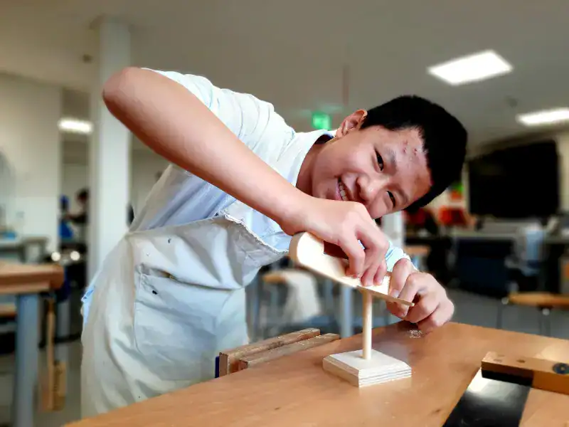 1. Student woodworking in a classroom at World Schools, focusing on practical learning and skill development.