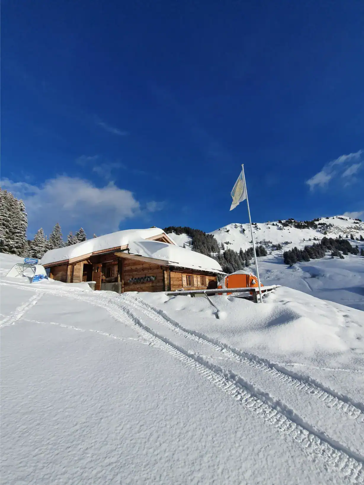 Snow-covered mountain cabin under clear blue sky, ideal for outdoor learning and nature-based education.