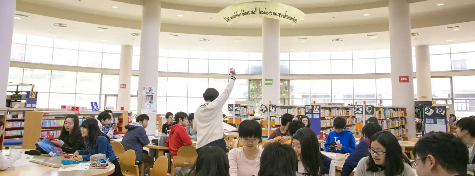 Bright school library interior filled with students studying and engaging in learning activities.