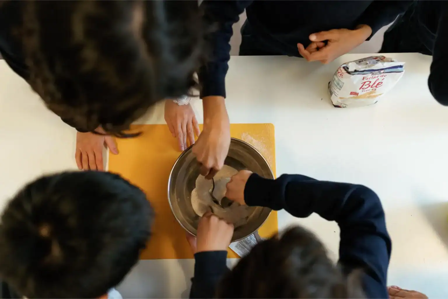 Fresh students baking bread in a school kitchen, developing culinary skills and teamwork.