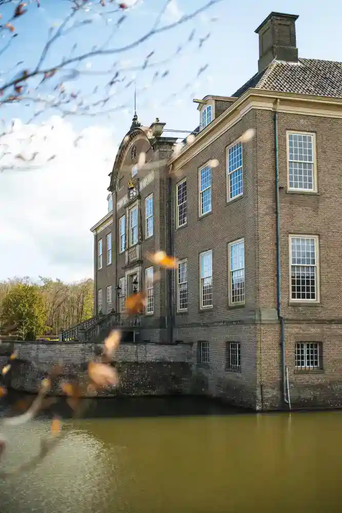 Elegant historic school building with large windows, situated beside a serene water body, embodying excellence in international education.