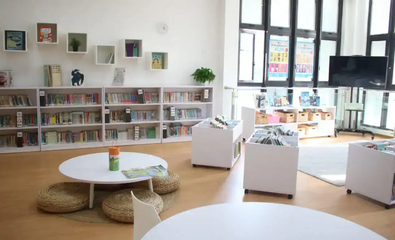 Bright modern school library with bookshelves, reading nooks, and large windows for optimal learning environment.