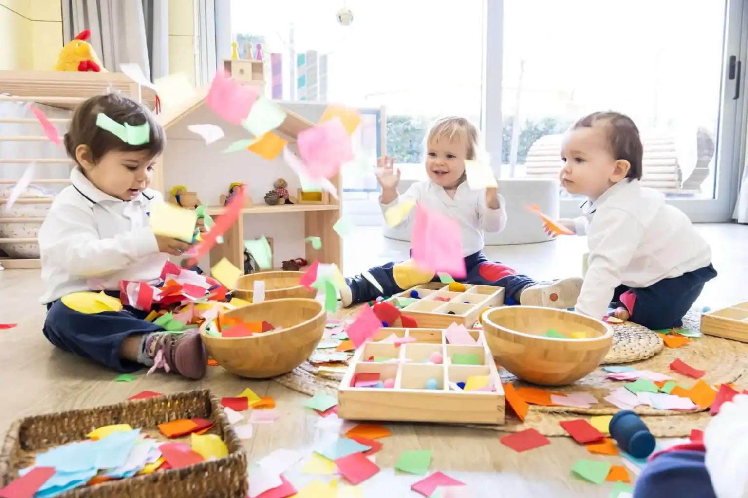 Colorful children playing with paper scraps in a vibrant classroom setting at World Schools.