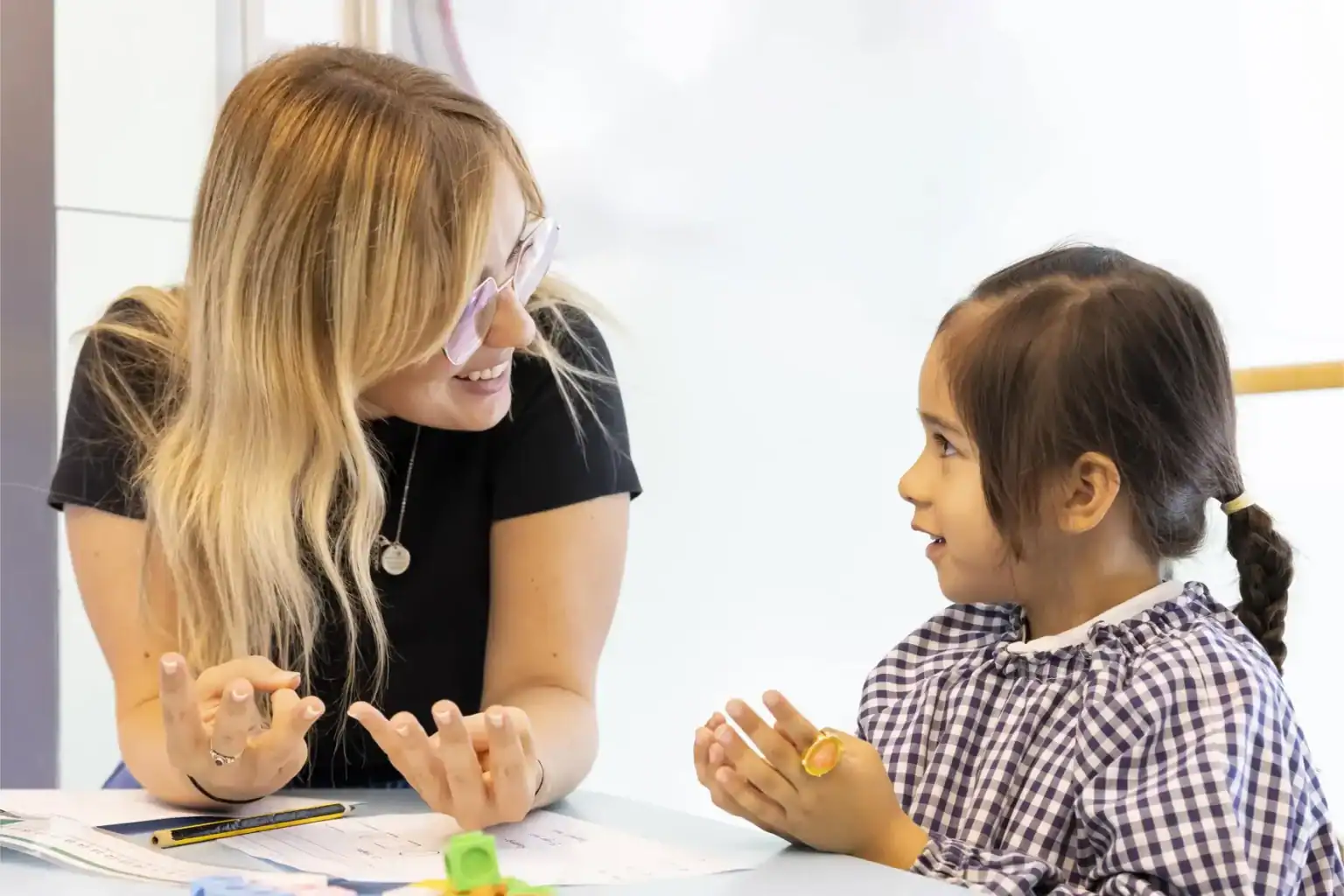 Caring teacher engaging with young student in classroom for quality education and learning support.